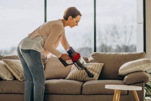 Kvinna dammsuger soffa hemma möbelvård